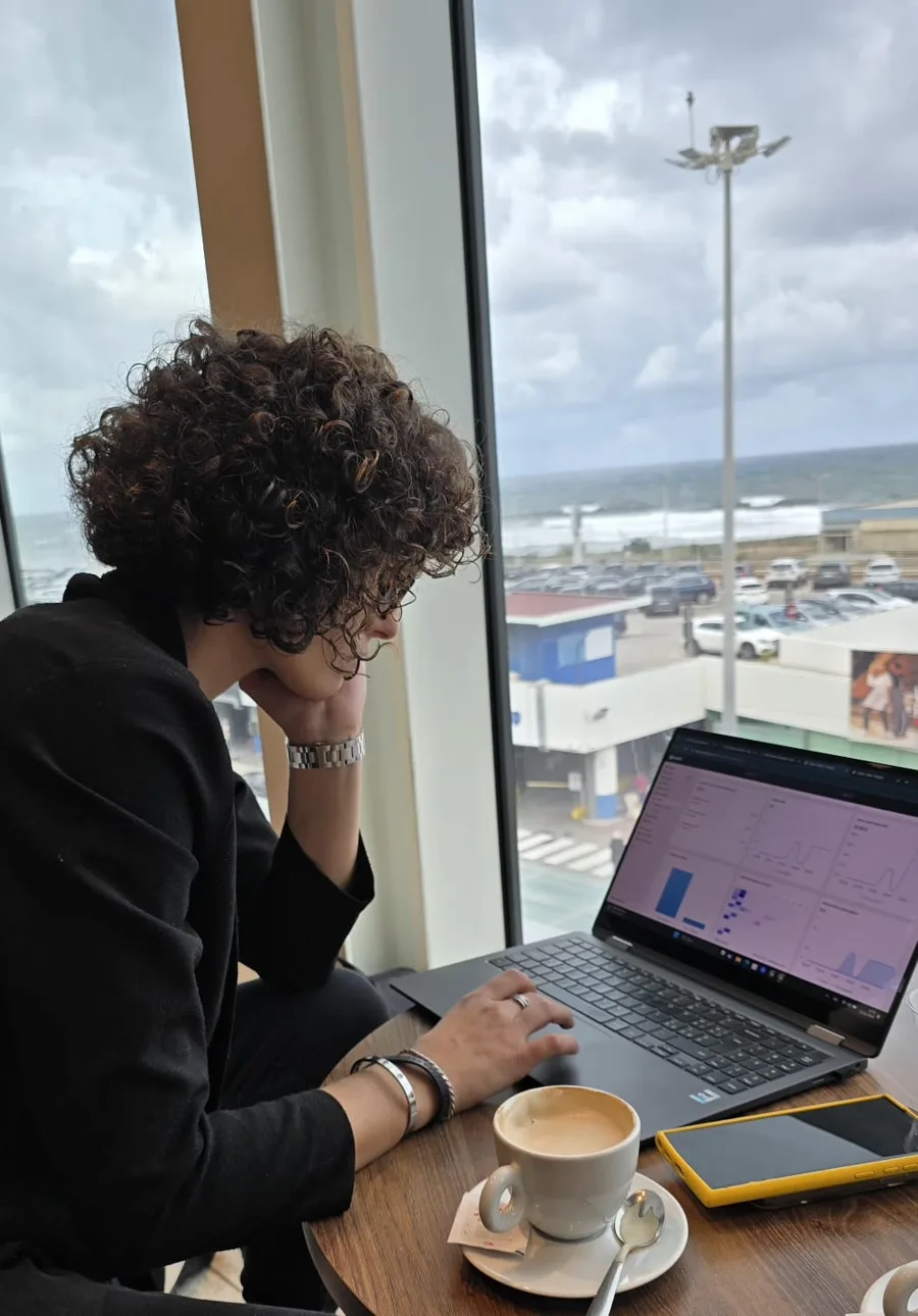 Simona al lavoro al computer, davanti a una vetrata sul mare